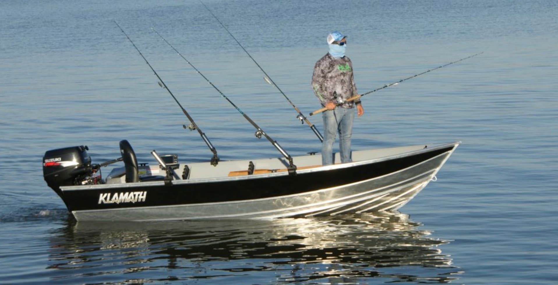 Angler fishing with multiple rods from a Klamath aluminum fishing boat on a calm reservoir