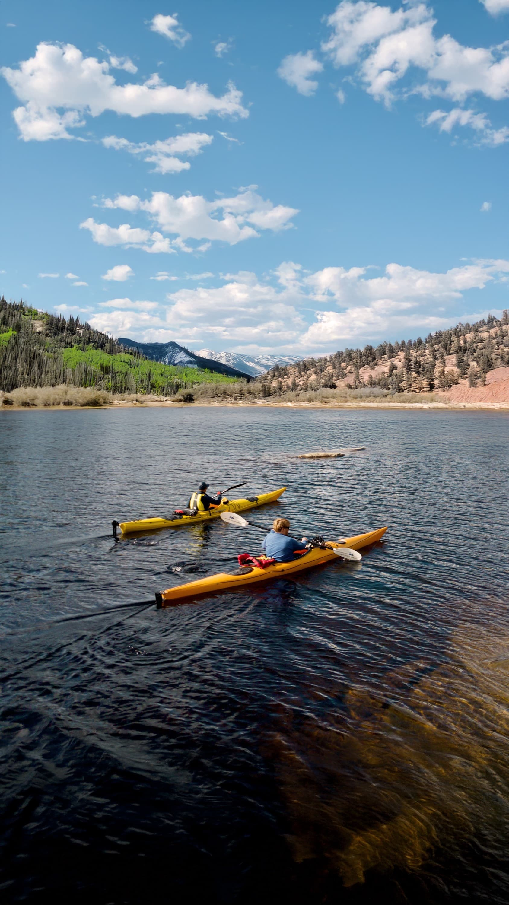 Two kayakers paddling on Jordanelle Reservoir with the Wasatch behind