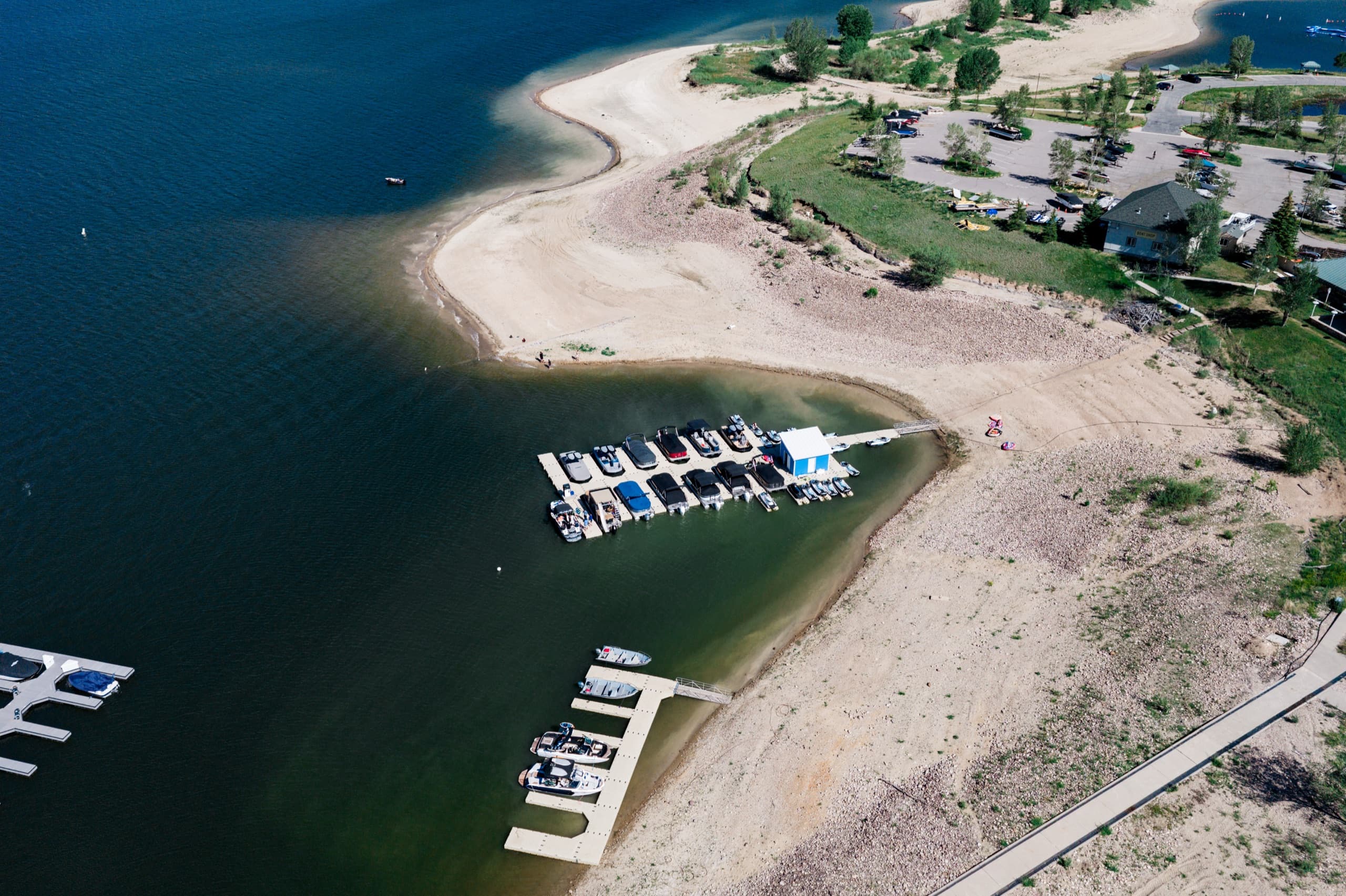 Aerial view of boats moored in a protected cove at Jordanelle Marina, with the jet-ski dock and beach alongside