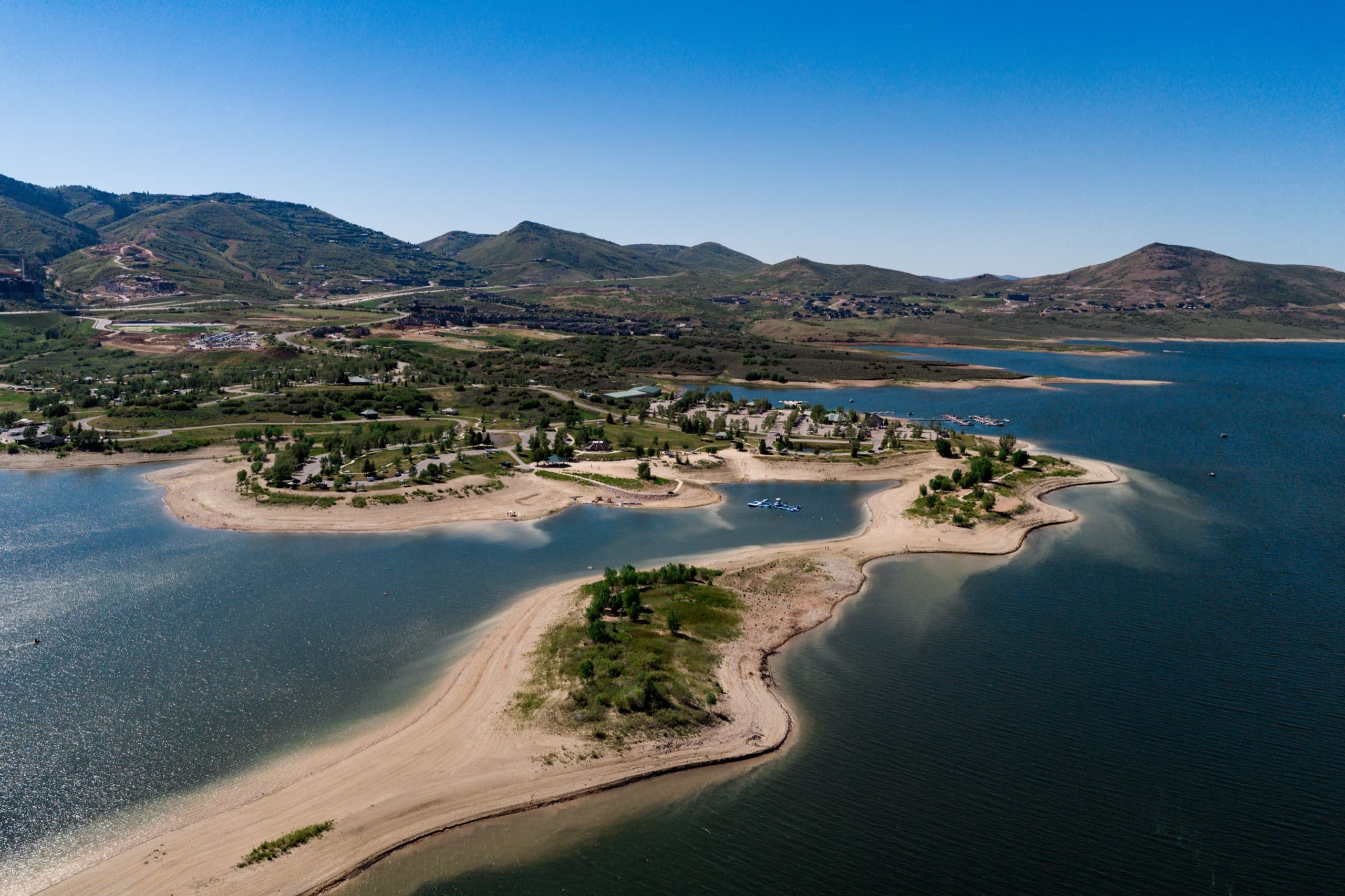 Aerial view of Jordanelle Reservoir's coves and beaches on a clear summer day, with boats on the water
