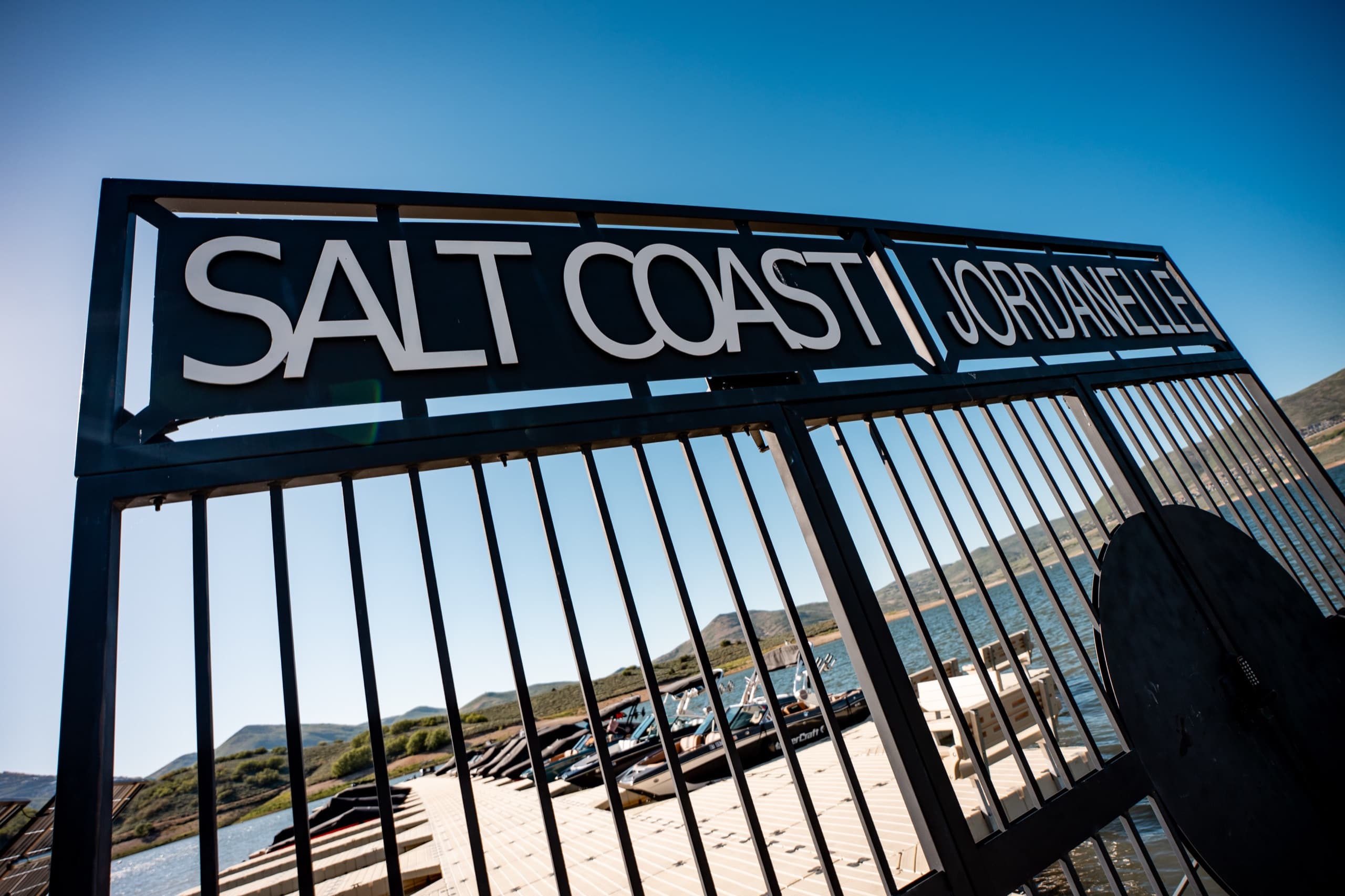 The Salt Coast Jordanelle entrance gate sign at the marina, with boat slips and the reservoir beyond