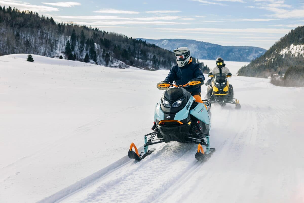 Riders on a guided Lofty Peaks snowmobile tour cutting through fresh mountain powder near Park City